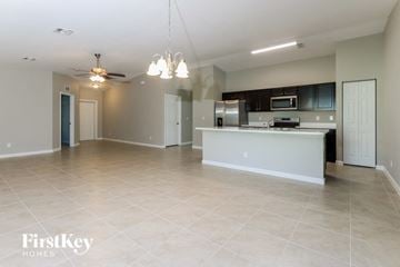 Port St. Lucie house for rent - A spacious kitchen and living room with a white kitchen island and a ceiling fan.