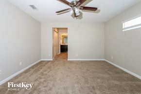 Port St. Lucie house for rent - A spacious room with a ceiling fan and a doorway leading to another room.
