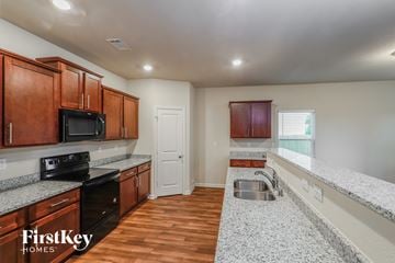 Pendergrass house for rent - A kitchen with wooden cabinets and a black stove top oven.