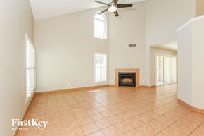 Phoenix house for rent - an empty living room with a fireplace and a ceiling fan