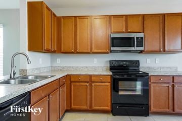 Cape Coral house for rent - a kitchen with wood cabinets and black appliances and a sink