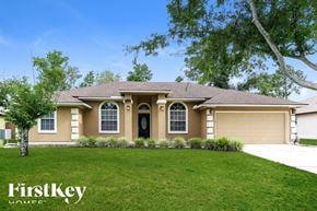Orange Park house for rent - A house with a brown roof and a black door is surrounded by greenery.