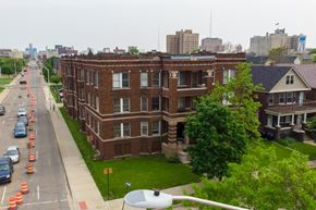 Detroit apartment for rent - A street view of a residential area with apartment buildings and cars parked on the side of the road.