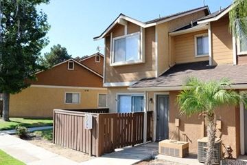 San Bernardino apartment for rent - a tan house with a wooden fence and a palm tree