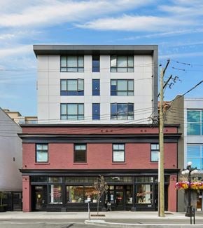 Victoria apartment for rent - A modern building with a red brick base sits on a street corner.