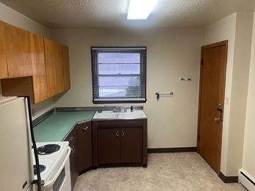 Fargo apartment for rent - A kitchen with a white refrigerator, a sink, and brown cabinets.