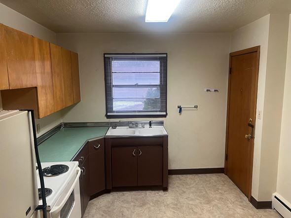 Fargo apartment for rent - A kitchen with a white refrigerator, a sink, and brown cabinets.