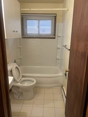 Fargo apartment for rent - A white toilet sits next to a bathtub in a bathroom.