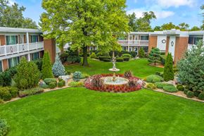 Bensenville apartment for rent - A courtyard with a fountain surrounded by trees and bushes.