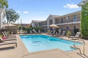 Des Plaines apartment for rent - A swimming pool surrounded by lounge chairs and umbrellas in a residential area.