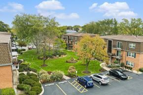 Worth apartment for rent - A parking lot with cars and apartment buildings in the background.