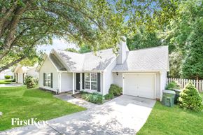 Greensboro house for rent - A white house with a garage is surrounded by greenery.