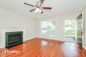 Greensboro house for rent - A room with a fireplace and a ceiling fan.