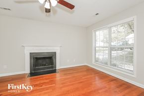 Greensboro house for rent - A room with a fireplace and a ceiling fan.