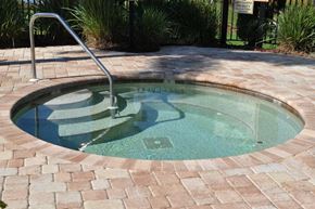 Bradenton house for rent - A hot tub with a metal staircase is surrounded by brick pavers.