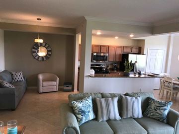Bradenton house for rent - A living room with a grey couch and a round mirror on the wall.