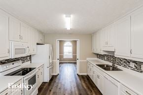 Loganville house for rent - an empty kitchen with white cabinets and white appliances