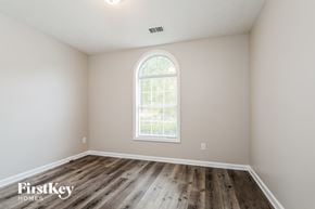 Loganville house for rent - the second bedroom with hardwood flooring and an arched window