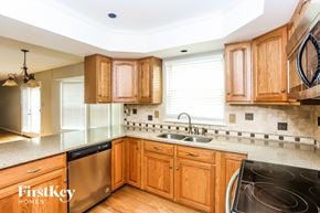Charlotte house for rent - a kitchen with wooden cabinets and stainless steel appliances and a sink