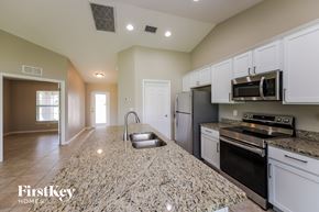 Cape Coral house for rent - a kitchen with white cabinets and granite counter tops and black appliances