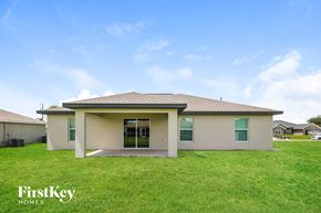 Cape Coral house for rent - the view of the exterior of a home with green grass and a blue sky