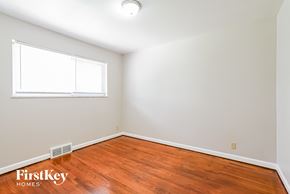Saint Louis house for rent - a bedroom with wood floors and white walls and a window