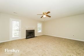 Greensboro house for rent - A spacious room with a fireplace and a ceiling fan.