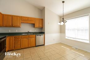 High Point house for rent - a kitchen with wooden cabinets and tiled floors and a large window