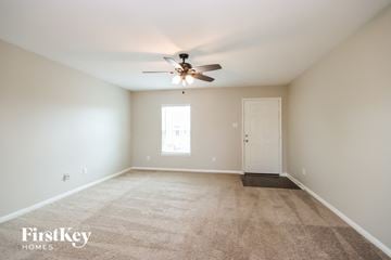 Cove house for rent - a spacious living room with carpet and a ceiling fan