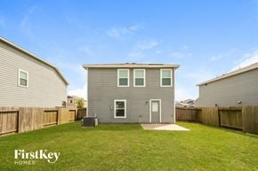 Cove house for rent - a backyard with a gray house and a grassy yard