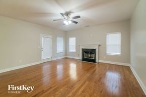 Newnan house for rent - an empty living room with a fireplace and a ceiling fan
