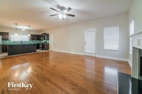 Newnan house for rent - an empty living room and kitchen with wood flooring and a ceiling fan
