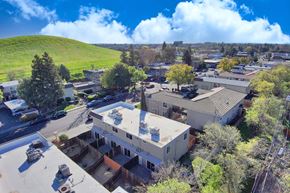 Vacaville apartment for rent - an aerial view of a building with a green hill in the background