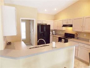 Bradenton house for rent - A kitchen with a black refrigerator and white cabinets.