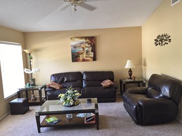 Bradenton house for rent - A living room with a brown leather couch and a glass coffee table.