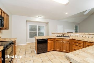 Greensboro house for rent - a kitchen with wooden cabinets and tile floors and a black dishwasher