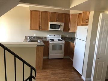 Prince Albert house for rent - a kitchen with wooden cabinets and a white stove and refrigerator