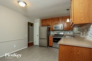 Saint Louis house for rent - A kitchen with wooden cabinets and a stainless steel refrigerator.