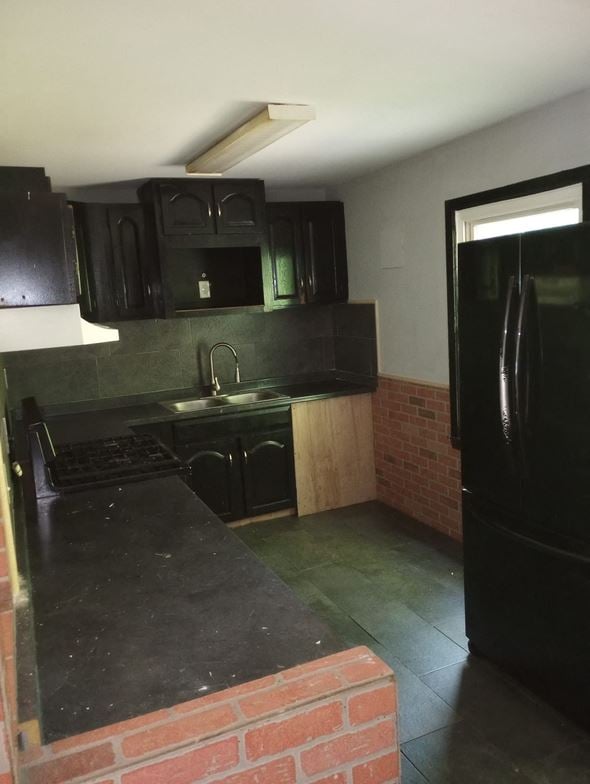 Cincinnati house for rent - A kitchen with black cabinets and a brick wall.
