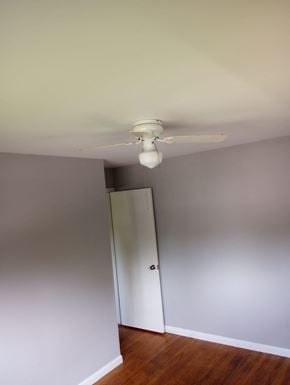 Cincinnati house for rent - A white ceiling fan hangs from a ceiling in a room with a wooden floor and white walls.
