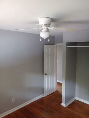 Cincinnati house for rent - A white ceiling fan hangs over a wood floor in a room.