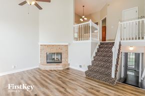 Shawnee house for rent - A living room with a fireplace and a staircase.