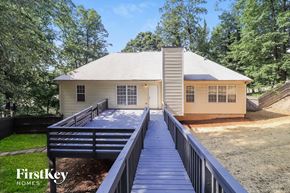 Cartersville house for rent - A house with a porch and a deck is surrounded by trees.