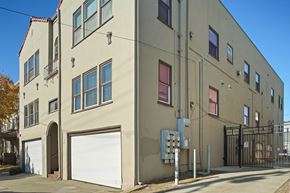 Berkeley apartment for rent - A beige building with a white garage door and a black gate.