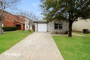 Sanantonio house for rent - A house with a garage and a tree in front.