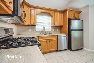 Baytown house for rent - a kitchen with wooden cabinets and a stove and a refrigerator