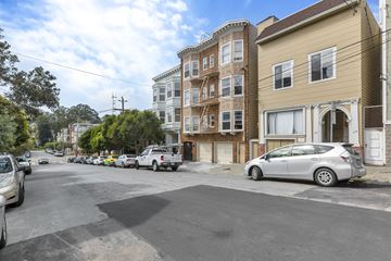 San Francisco apartment for rent - A street view with cars parked on the side and buildings in the background.