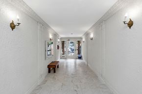 San Francisco apartment for rent - A long white hallway with a bench and wall sconces.