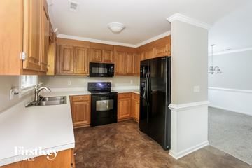 Charlotte house for rent - A kitchen with wooden cabinets and black appliances.