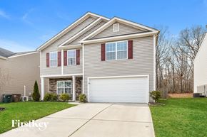 Greensboro house for rent - a beige house with a white garage door and a green lawn